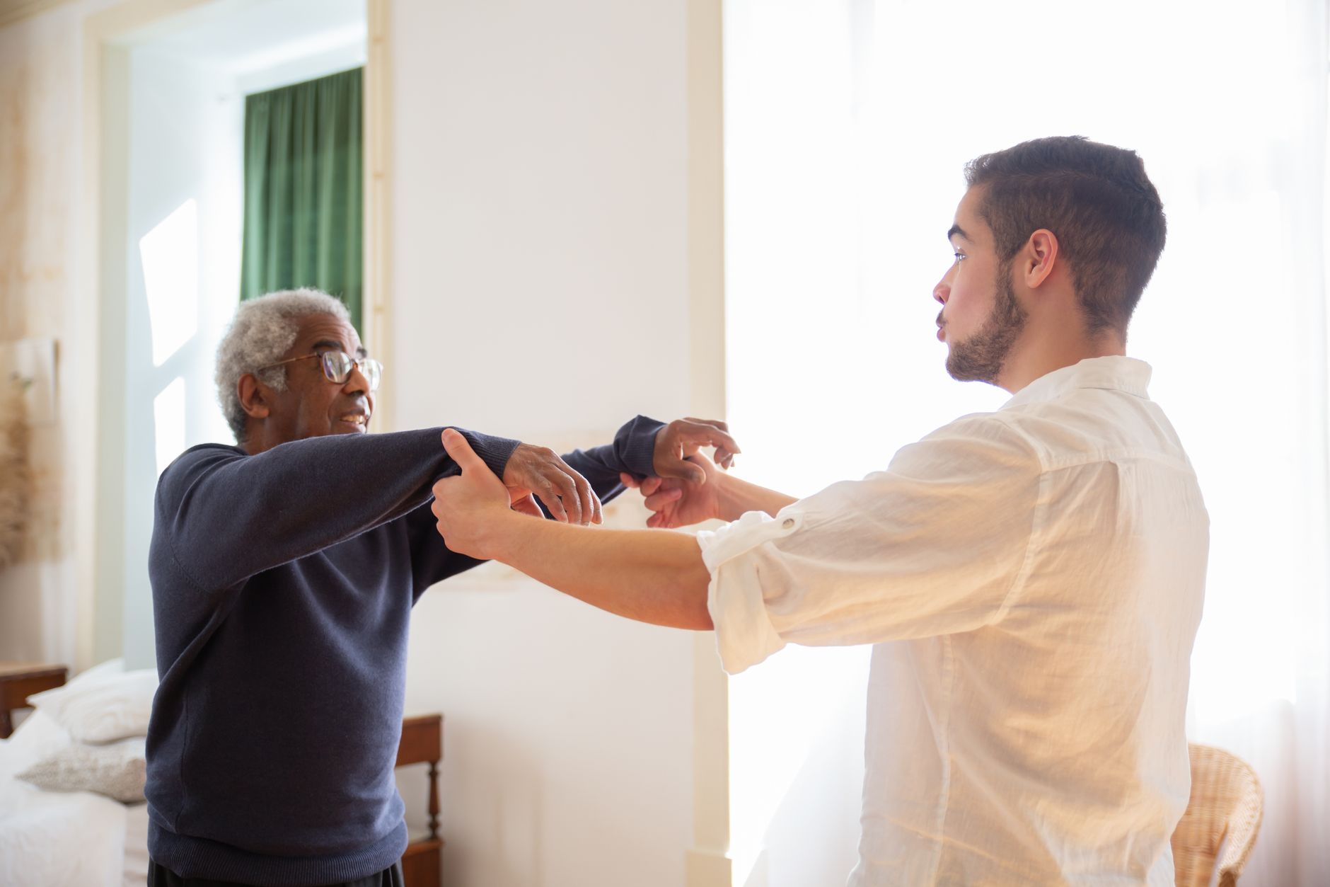 Nurse assisting a senior man to stand up gently